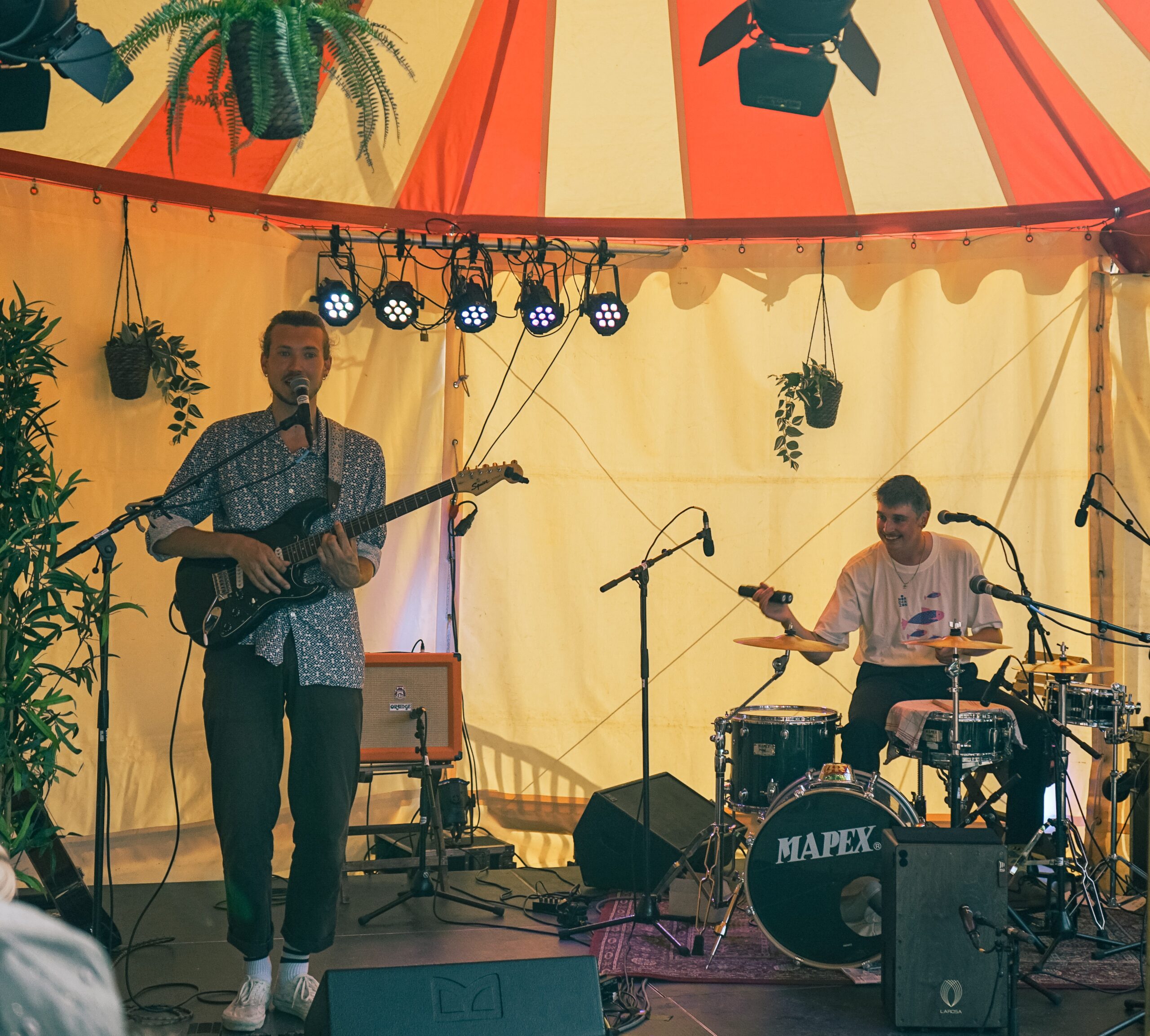 Joost op gitaar en Joek op drums in een geel, rode tent 